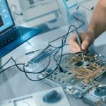 Electronics repair background. Hand of male tech testing motherboard. Shallow DOF, focus on the hand and part of the motherboard. This image is toned.
