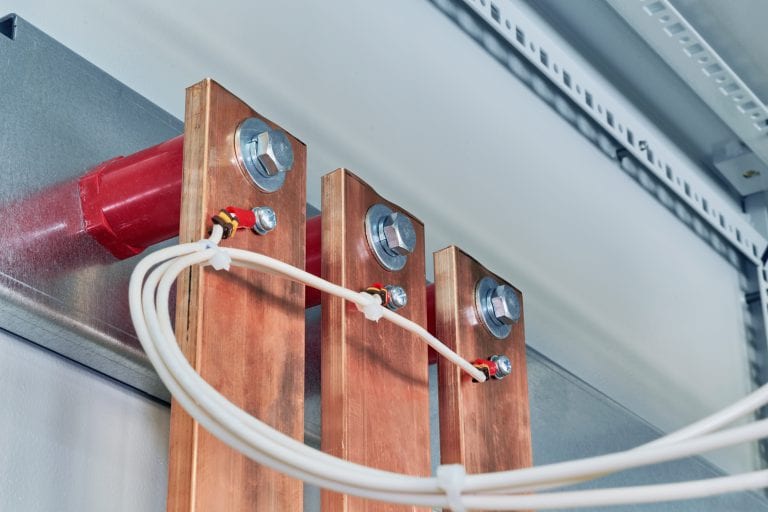 Electrical wires are connected to copper busbars. Busbars are fixed to the circuit Board through red insulators. Electrical equipment is installed in the enclosure of the electrical Cabinet.