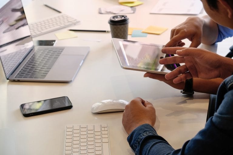 Website designer planning and meeting application development layout framework and coding program on paper and computer.