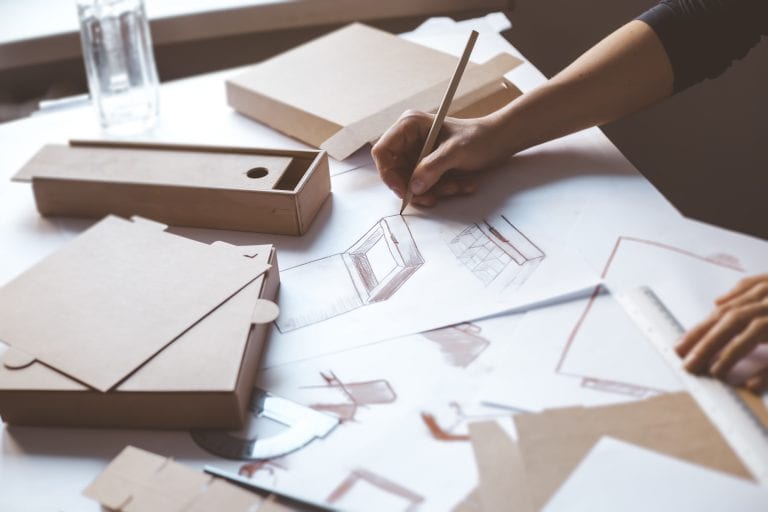 Designer draws a mockup for crafting cardboard box. Development of packaging design sketch.