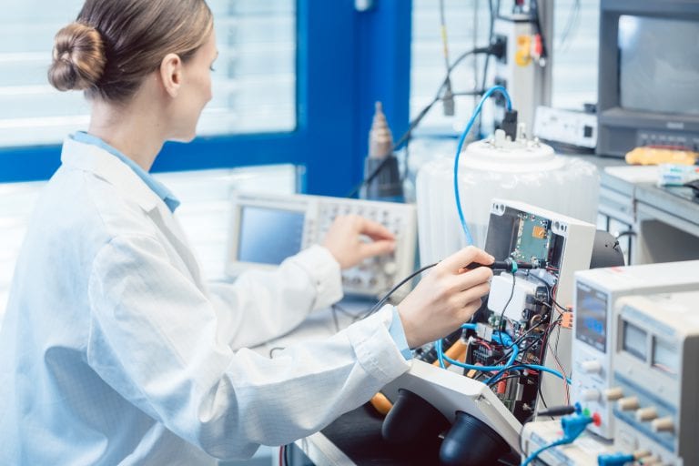 Engineer woman measuring electronic product on test bench in her lab for EMC compliance