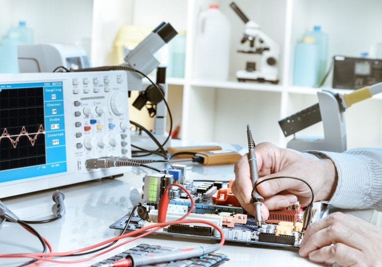 Electronics repair service, hands of senior tech reparing an electronic circuit