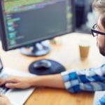 Close up shot of a young software developer, programmer  working at his desk