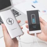 Man connecting USB charger to smart phone. Power bank, mobile phone battery on desk concept